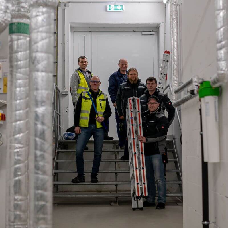 6 Experten der SSN Gebäudetechnik stehen auf einer Treppe und lächeln in die Kamera